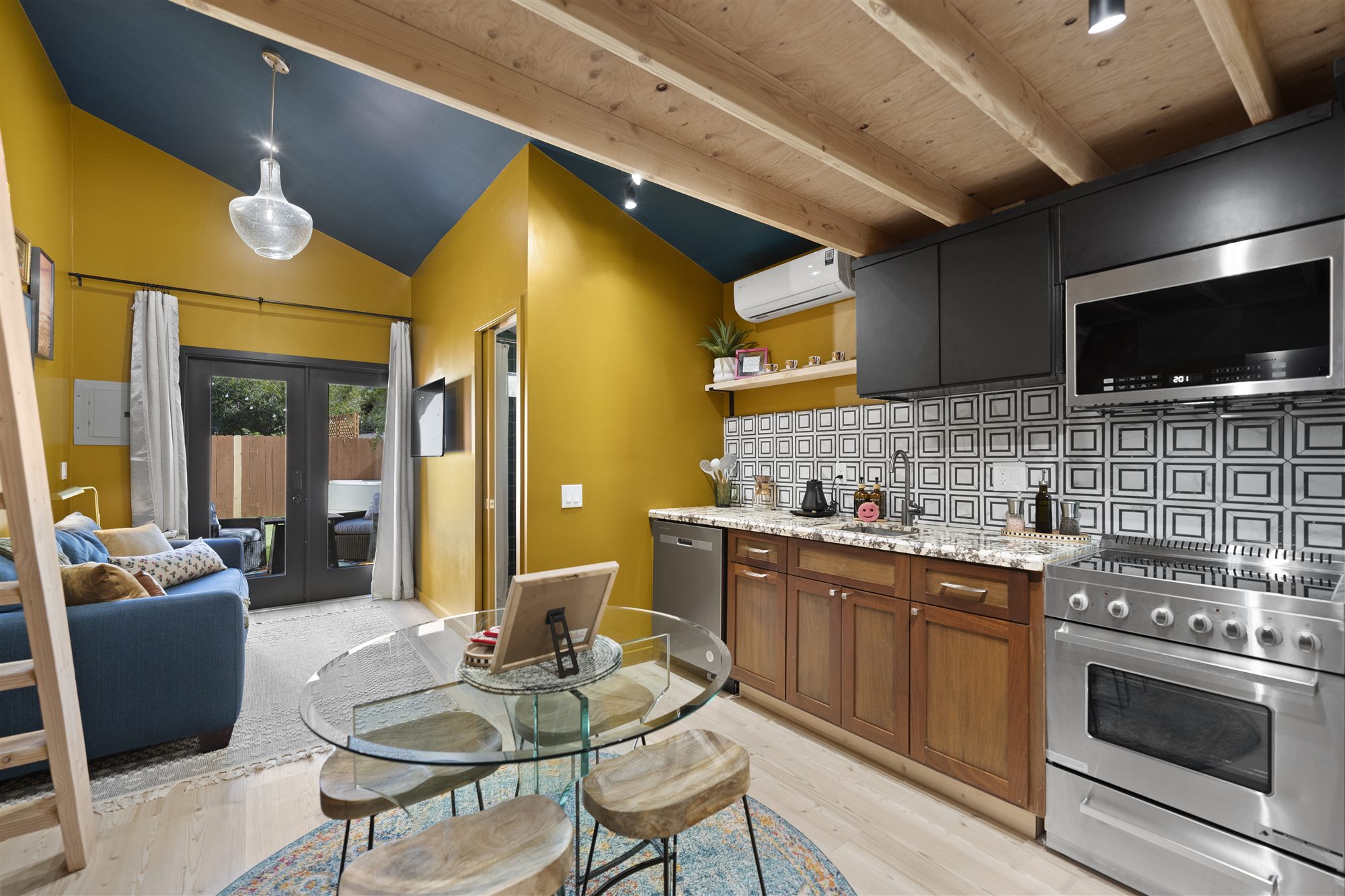 Kitchen and dining area with wood beam ceiling, patterned tile backsplash and gas range