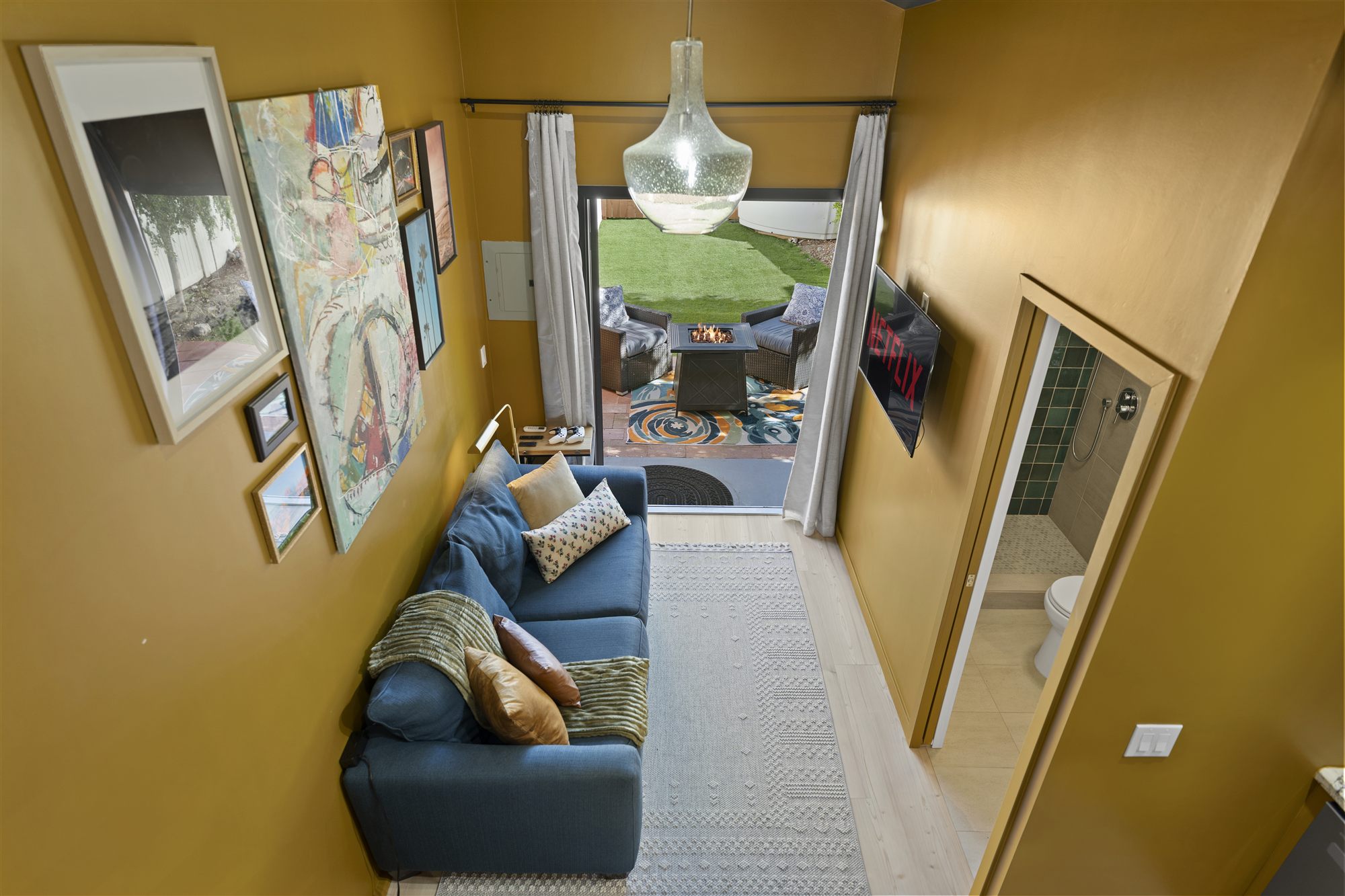 Bird's-eye view down into the living room toward the open patio door and gallery wall
