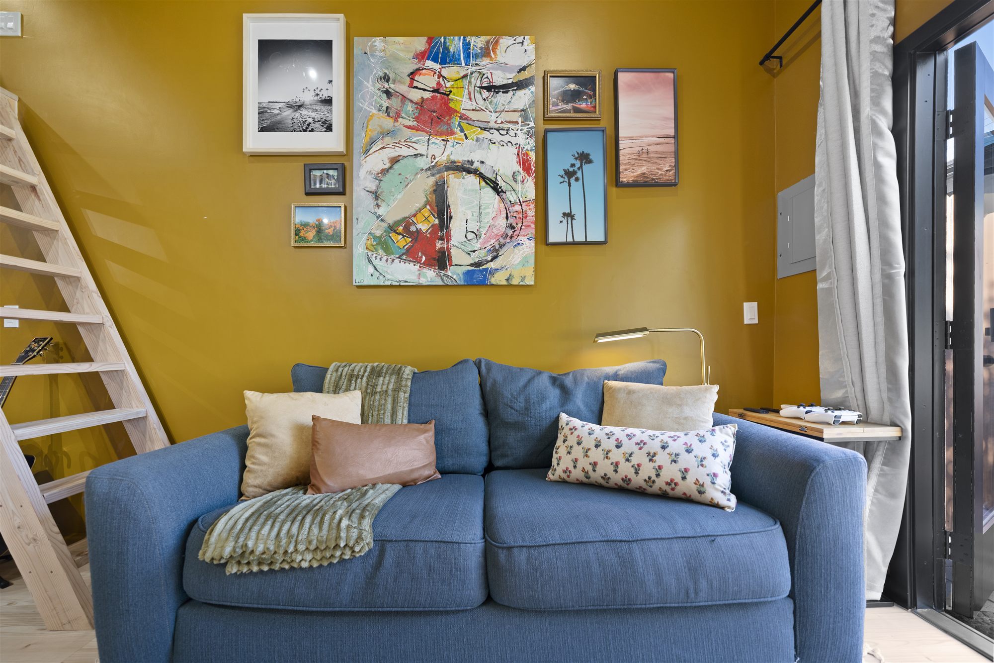 Sofa close-up with gallery wall above featuring coastal black-and-white photography and an abstract painting