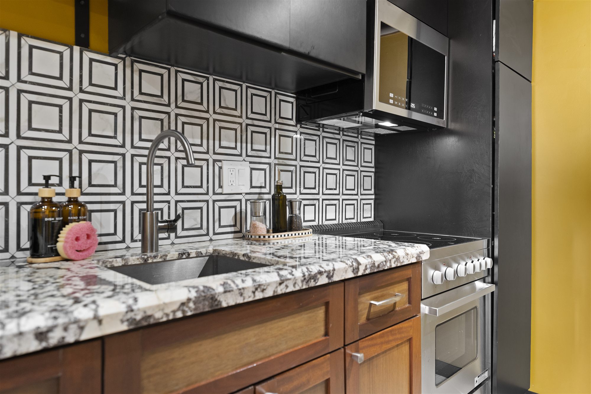 Kitchen sink close-up with graphic tile backsplash and gas range